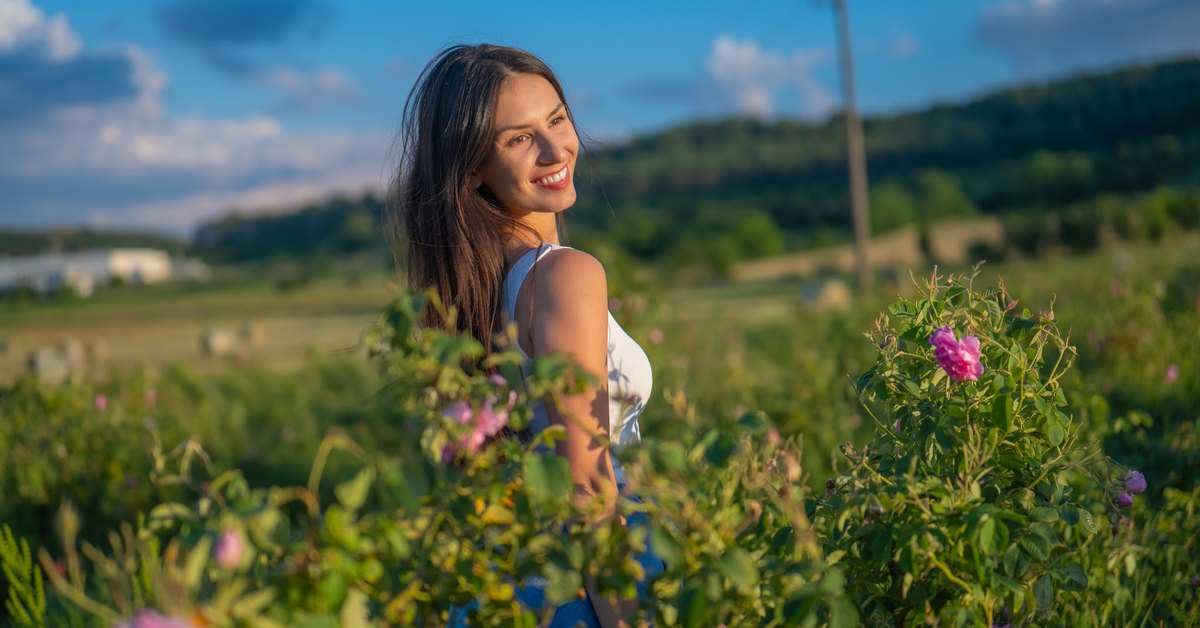 Kvinna på ett blommande rosfält i den bulgariska Rosornas dal