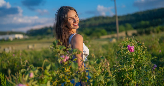 Kvinna på ett blommande rosfält i den bulgariska Rosornas dal